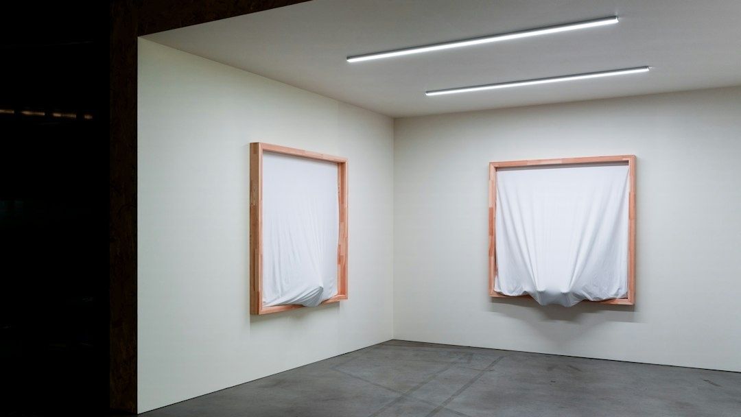 Minimalistiskt galleri med två tygklädda verk i trästommar